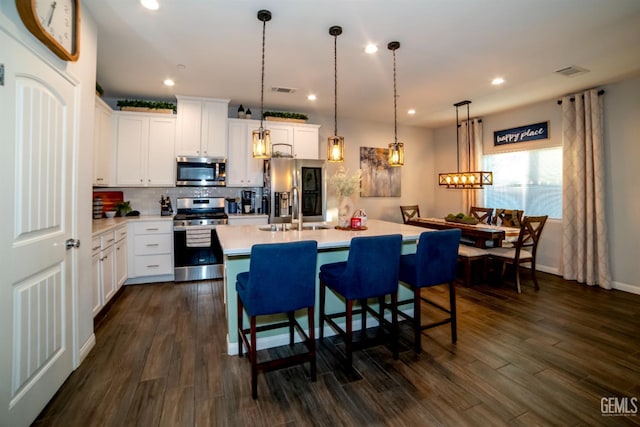 8414 Kowa St, Bakersfield, CA 93314 - kitchen featuring appliances with stainless steel finishes, light countertops, backsplash, a kitchen island with sink, and dark wood-style flooring