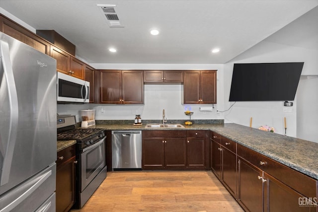 kitchen featuring stainless steel appliances, sink, dark stone countertops, and light hardwood / wood-style floors