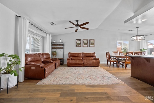 living room featuring hardwood / wood-style floors, ceiling fan with notable chandelier, and vaulted ceiling