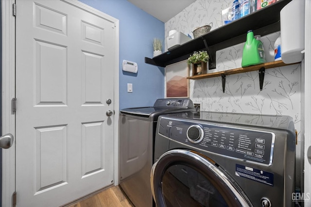 clothes washing area with separate washer and dryer and light wood-type flooring