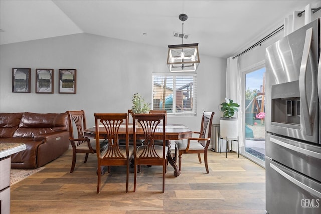 dining room featuring lofted ceiling, wood-type flooring, and an inviting chandelier