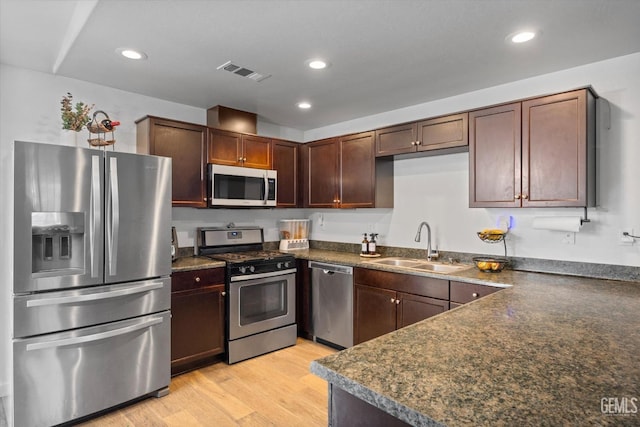 kitchen with dark brown cabinetry, sink, light wood-type flooring, and appliances with stainless steel finishes