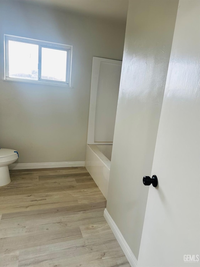 bathroom featuring wood-type flooring, toilet, and a bathing tub