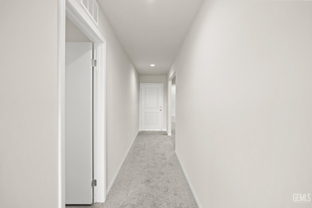 hallway featuring baseboards, light colored carpet, recessed lighting, and visible vents