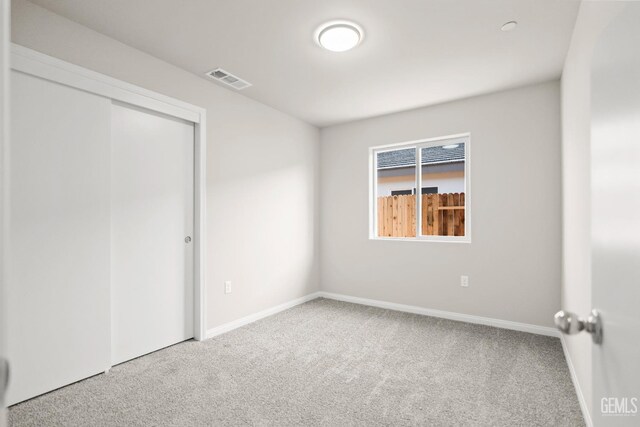 unfurnished bedroom featuring carpet floors, baseboards, visible vents, and a closet