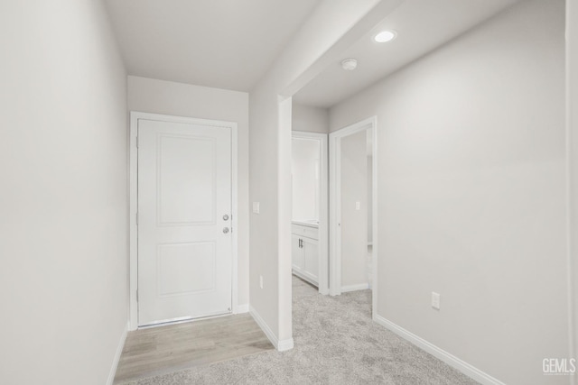 hallway with baseboards, recessed lighting, and light carpet