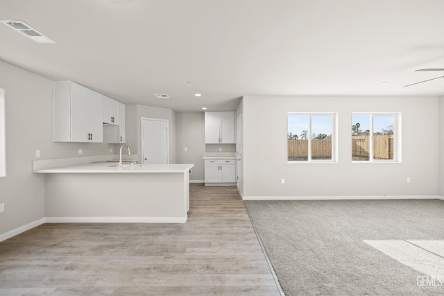 kitchen with visible vents, open floor plan, baseboards, and white cabinets