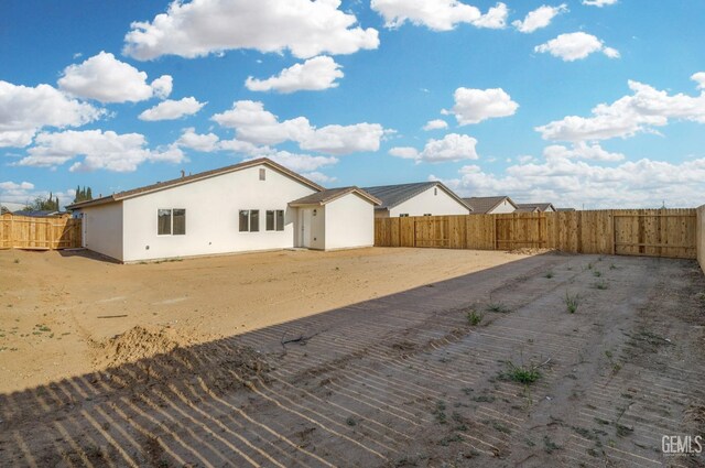 rear view of property with a fenced backyard and stucco siding