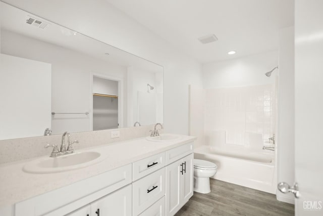bathroom with a sink, double vanity, toilet, and wood finished floors