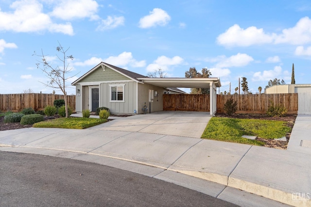 view of front facade with board and batten siding, an attached carport, fence, and driveway