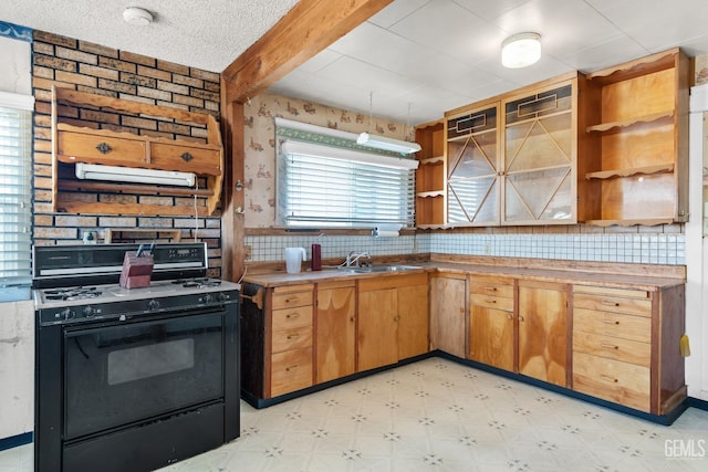 kitchen featuring black gas range oven, sink, backsplash, beam ceiling, and a textured ceiling