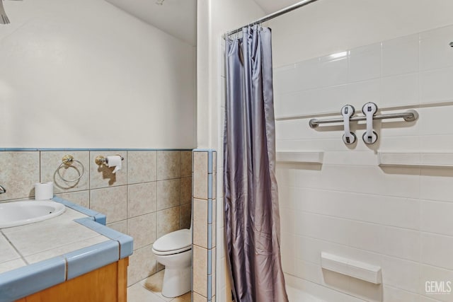 bathroom with tile walls, vanity, tile patterned flooring, and toilet