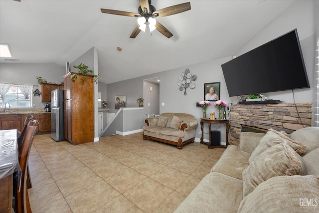 living room with light tile patterned floors, baseboards, lofted ceiling, and a stone fireplace