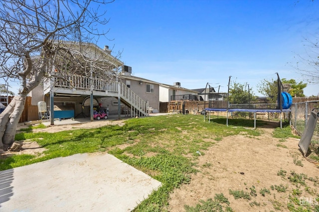 view of yard with stairs, a trampoline, and a fenced backyard