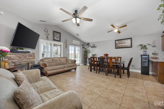 living area with light tile patterned floors, visible vents, lofted ceiling, and a stone fireplace