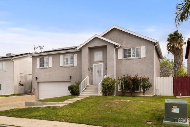 bi-level home featuring stucco siding, a front yard, and fence