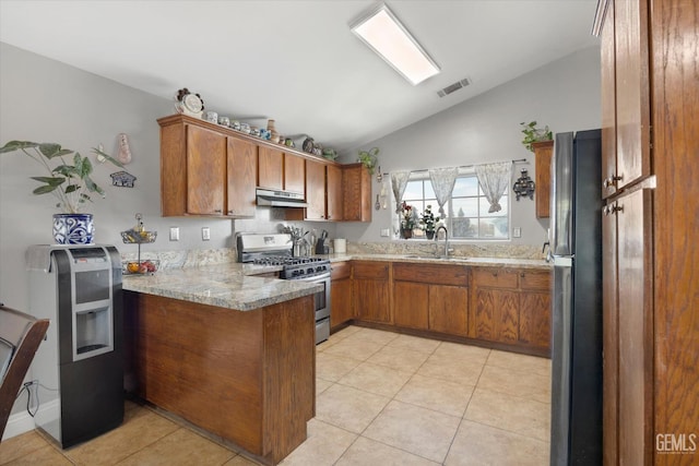 kitchen featuring visible vents, under cabinet range hood, brown cabinets, a peninsula, and stainless steel gas range