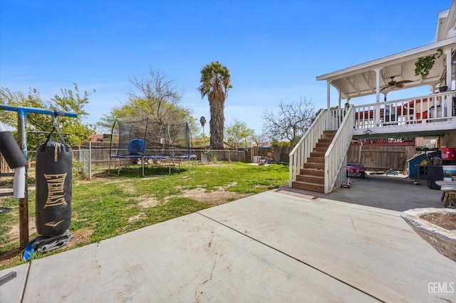 view of yard with stairs, a patio, a trampoline, and a fenced backyard