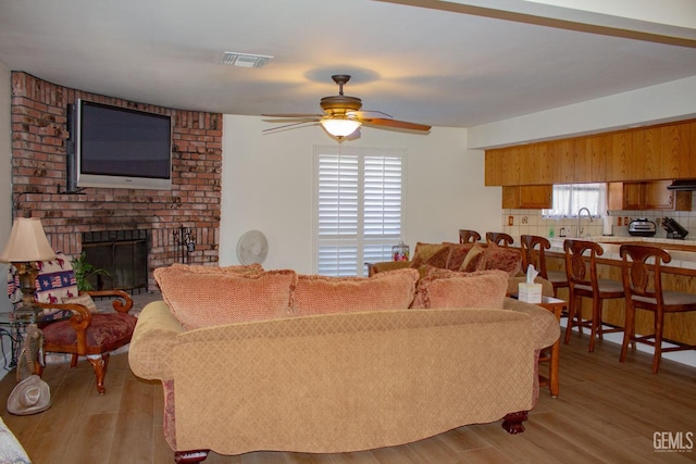 1301 Charterten Ave, Bakersfield, CA 93307 - living area with ceiling fan, a brick fireplace, and wood finished floors