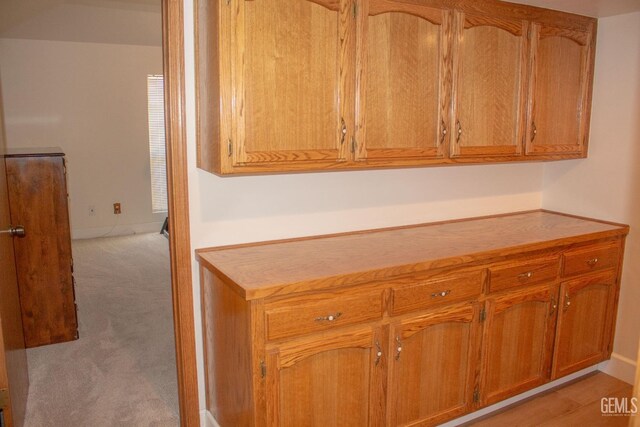 1301 Charterten Ave, Bakersfield, CA 93307 - kitchen featuring light carpet, brown cabinets, light countertops, and baseboards
