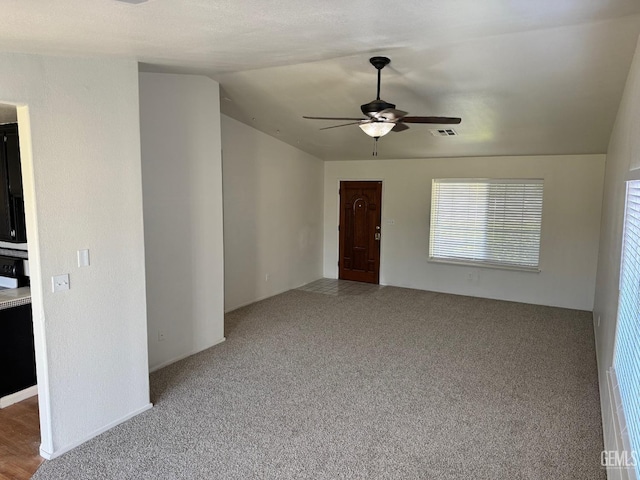 carpeted spare room featuring ceiling fan and vaulted ceiling