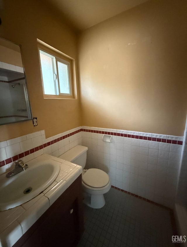 bathroom featuring tile patterned floors, vanity, tile walls, and toilet