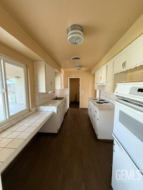 kitchen featuring white cabinets, decorative backsplash, and white appliances