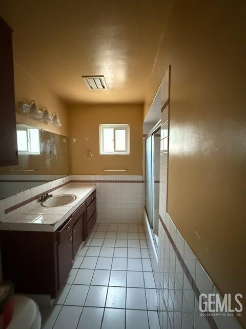 bathroom with tile patterned floors, vanity, an enclosed shower, and toilet