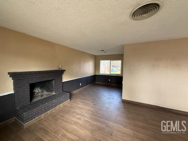 unfurnished living room with a textured ceiling and a brick fireplace