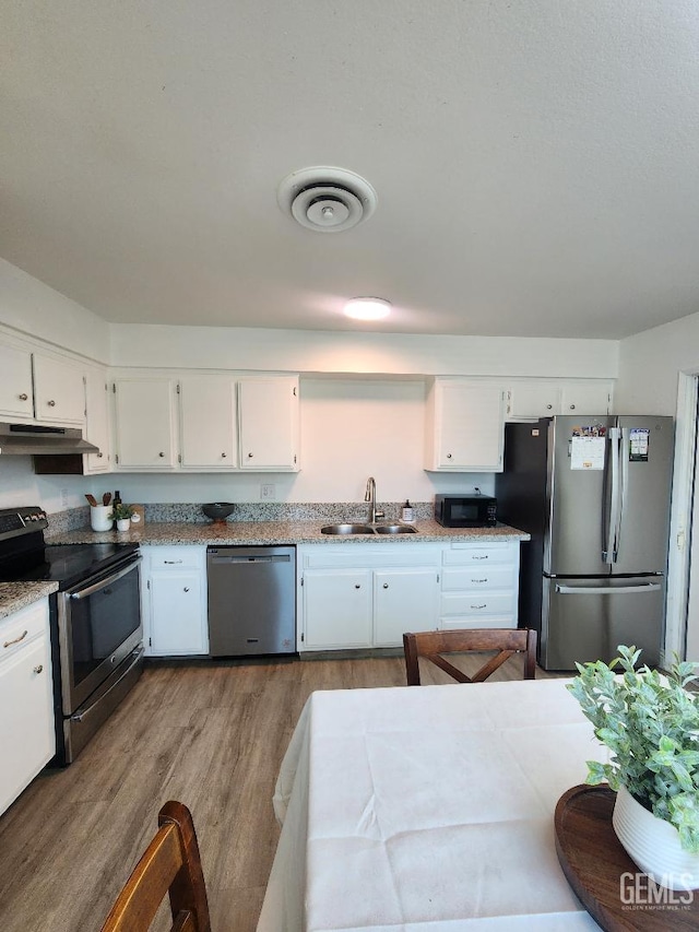 5812 Appletree Ln, Bakersfield, CA 93309 - kitchen featuring stainless steel appliances, under cabinet range hood, wood finished floors, and white cabinetry