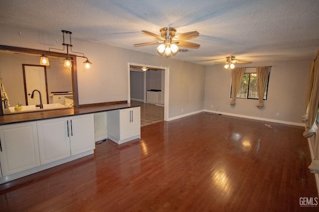 interior space with a textured ceiling, dark wood-type flooring, a sink, and baseboards