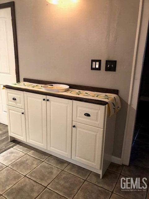 kitchen with appliances with stainless steel finishes, dark countertops, tile patterned flooring, and white cabinets