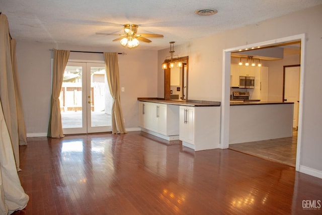 unfurnished living room featuring a textured ceiling, visible vents, a ceiling fan, french doors, and hardwood / wood-style floors