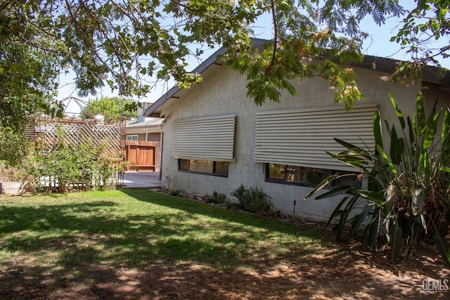 back of property with a yard, a patio area, fence, and stucco siding