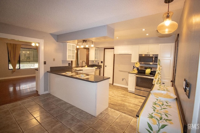 kitchen with light tile patterned floors, stainless steel appliances, a peninsula, white cabinets, and glass insert cabinets