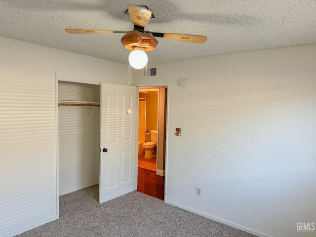 unfurnished bedroom featuring a textured ceiling, visible vents, a ceiling fan, a closet, and carpet