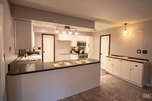 kitchen featuring a peninsula, dark countertops, white cabinetry, and stainless steel appliances