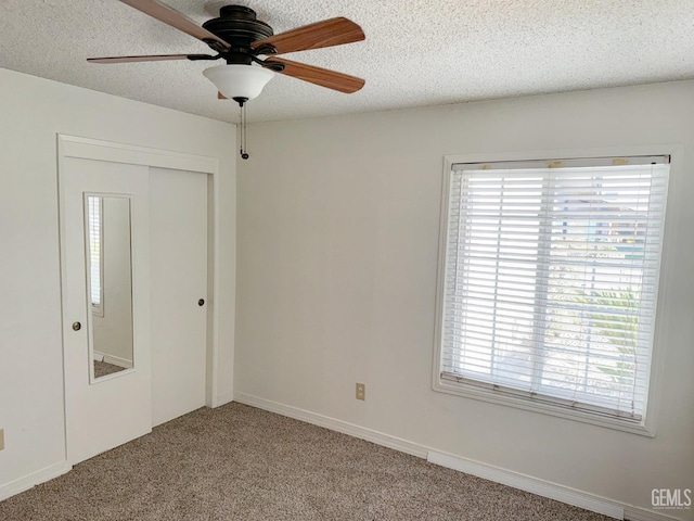 spare room featuring a ceiling fan, a textured ceiling, and light colored carpet