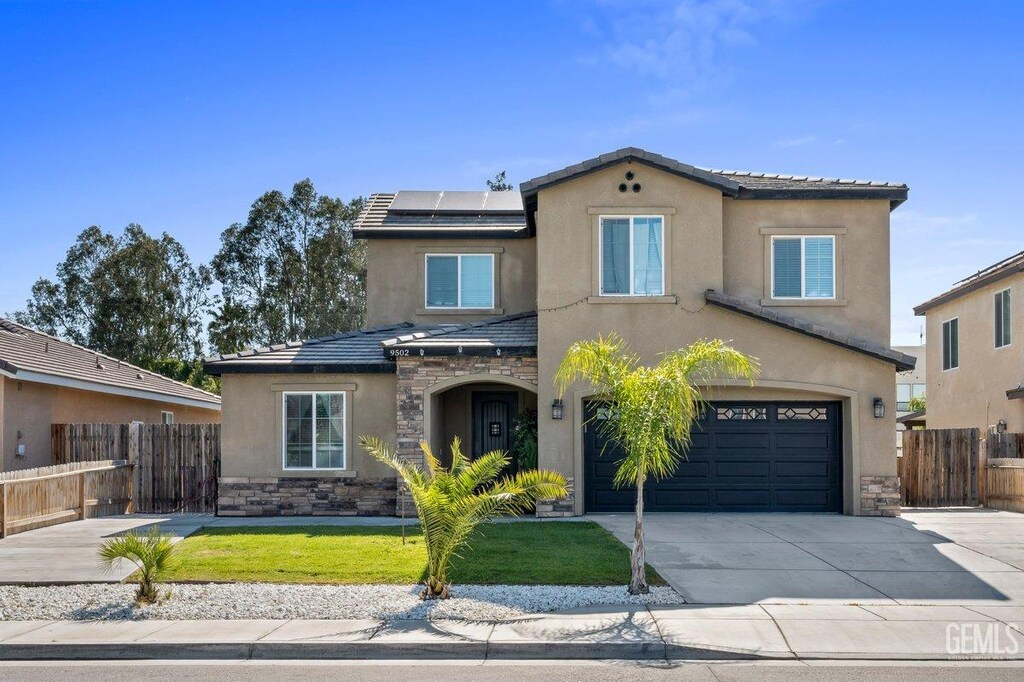 view of front of house featuring a garage, a front yard, and solar panels