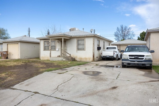 view of front of home with stucco siding, concrete driveway, and a shingled roof