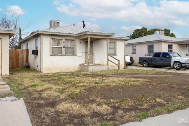 bungalow-style house with stucco siding and fence