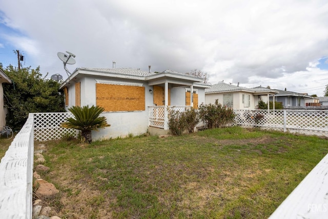 view of front of home featuring stucco siding, a front lawn, and fence