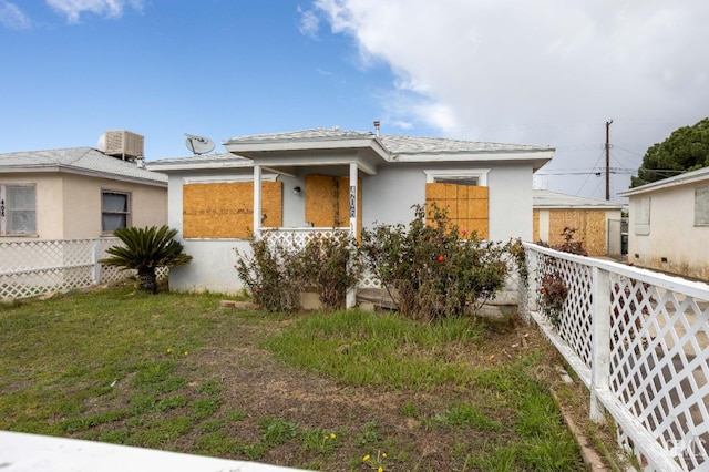 view of front of property featuring a front lawn, fence, and stucco siding