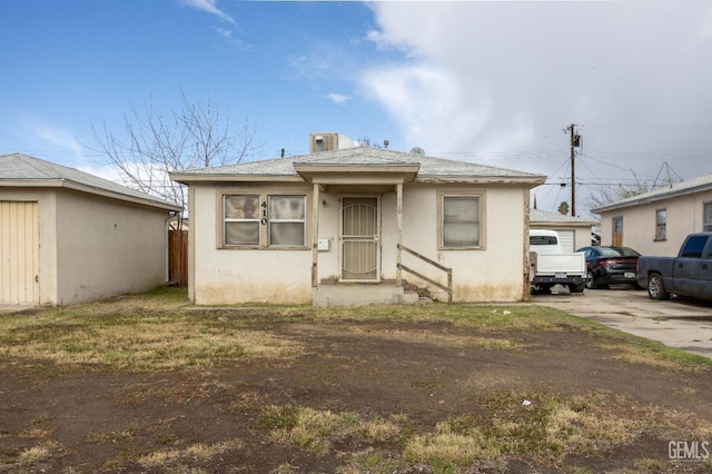 bungalow-style house with concrete driveway, cooling unit, and stucco siding