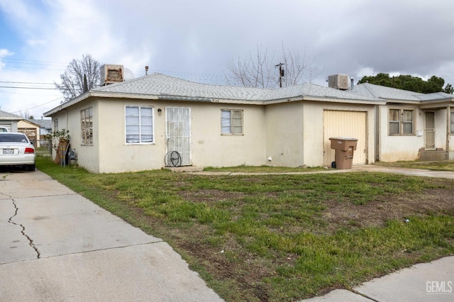 view of front of home featuring central air condition unit, stucco siding, concrete driveway, and a front lawn