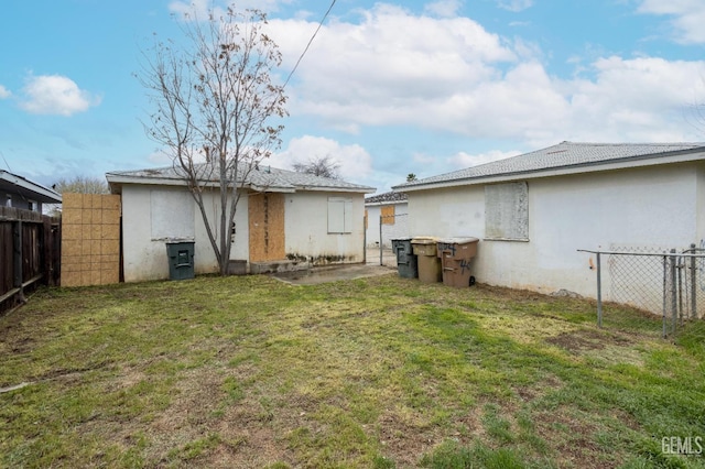 back of property featuring a yard, fence, and stucco siding