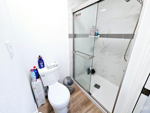 bathroom with an enclosed shower, hardwood / wood-style flooring, and toilet