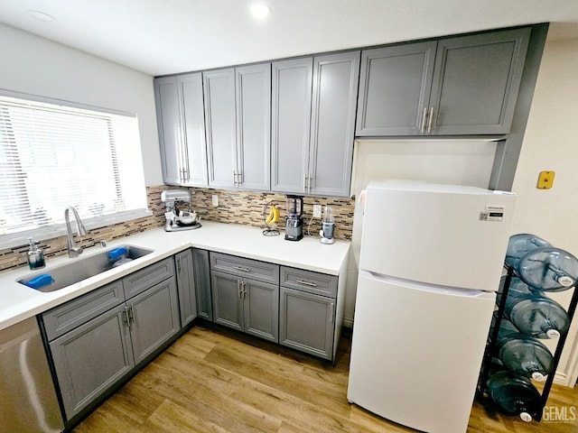 kitchen featuring sink, dishwasher, white fridge, decorative backsplash, and light wood-type flooring