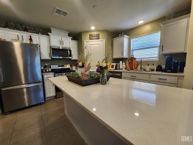 5911 Bogart Dr, Bakersfield, CA 93313 - kitchen with stainless steel appliances, white cabinets, dark tile patterned floors, light countertops, and recessed lighting