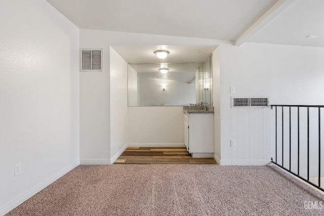 carpeted spare room featuring beam ceiling